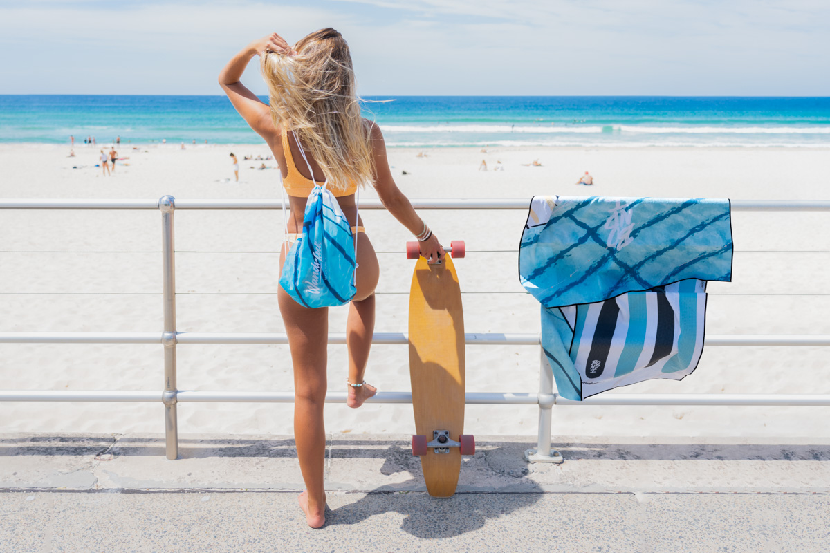 Wandrful Contact us. Skater girl with Wandrful backpack and beach towel at Bondi Beach.